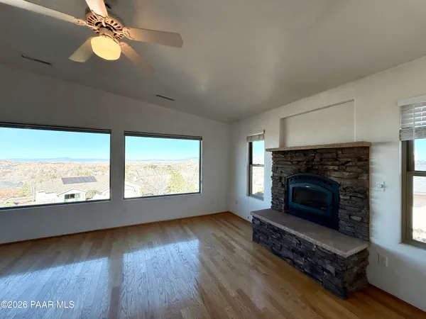 an empty room with wooden floor fireplace and windows