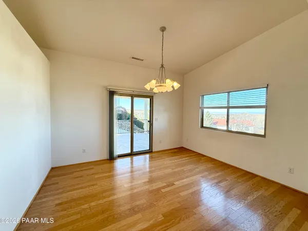 a view of an empty room with window and wooden floor