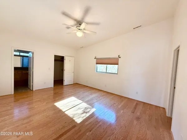 an empty room with wooden floor chandelier and windows