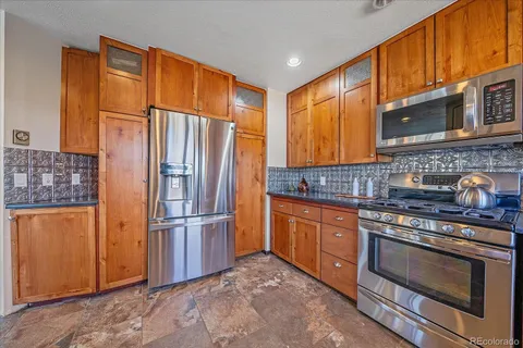a kitchen with stainless steel appliances granite countertop a refrigerator stove and sink