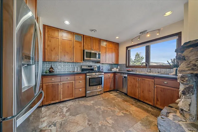 a kitchen with stainless steel appliances granite countertop a refrigerator a stove top oven and sink