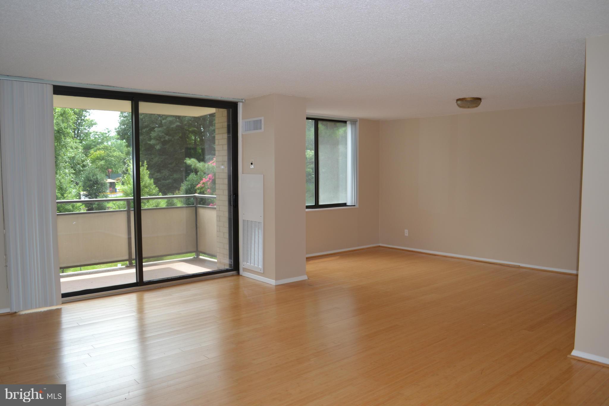5225 Pooks Hill Road, Unit 204S Bethesda, MD 20814 - Photo 3 of 14 an empty room with sliding glass door and wooden floor