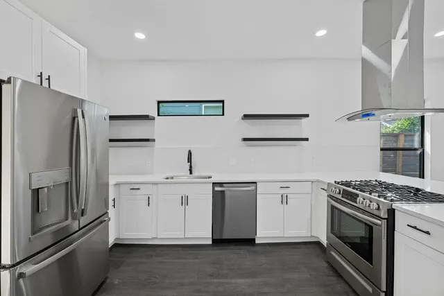 a kitchen with stainless steel appliances a stove a sink and a refrigerator