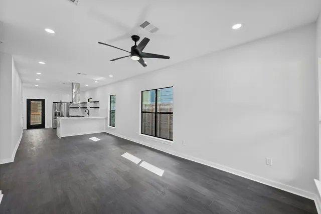 a view of an empty room with a kitchen and a window
