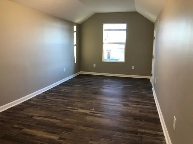 an empty room with wooden floor chandelier and windows