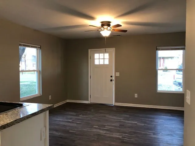 an empty room with wooden floor and windows