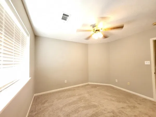 an empty room with windows and ceiling fan