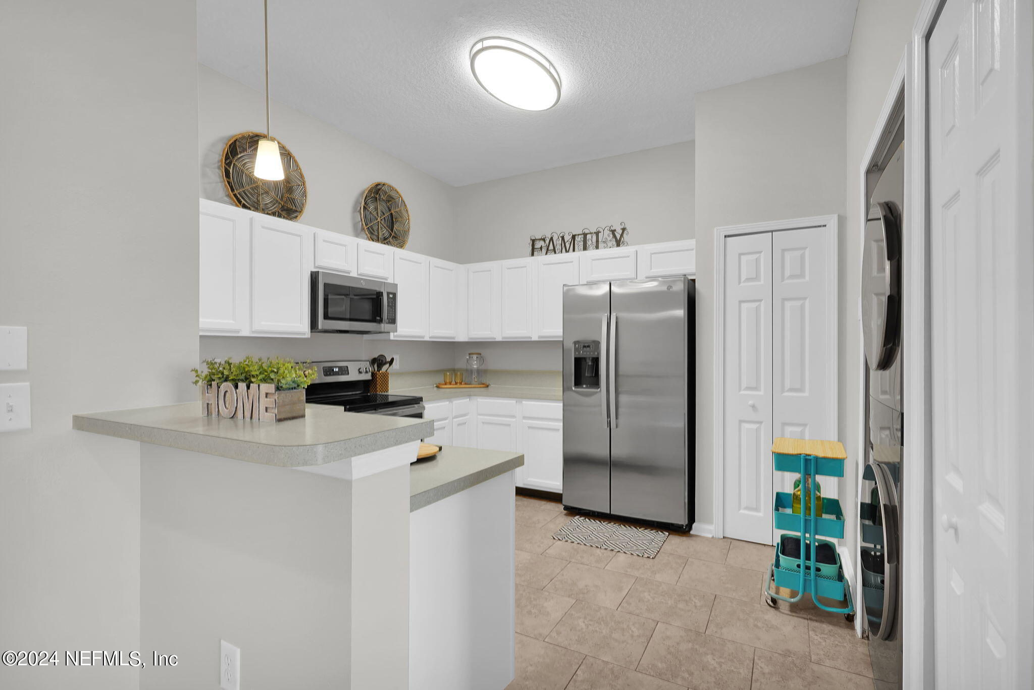 a kitchen with stainless steel appliances a refrigerator a sink a stove a microwave a sink and white cabinets