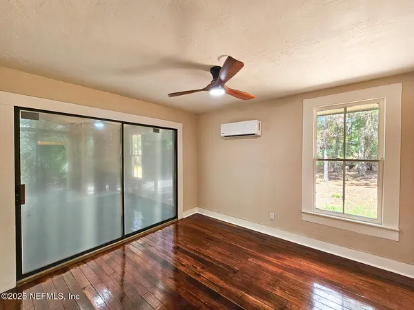 a view of empty room with wooden floor and fan