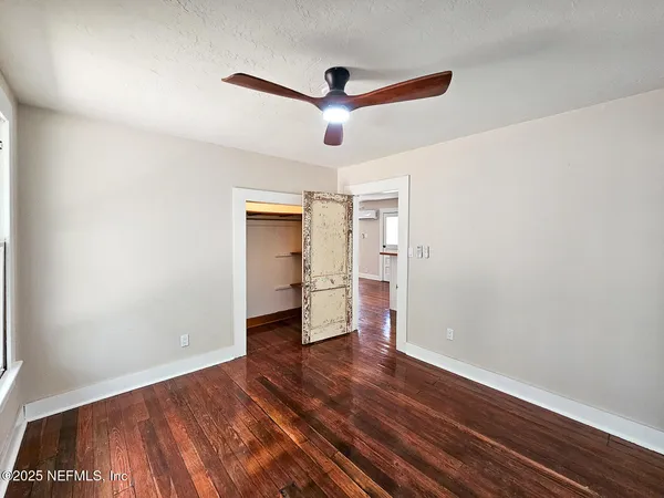 a view of empty room with wooden floor and ceiling fan