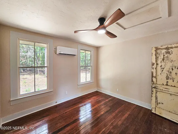 a view of empty room with wooden floor and fan
