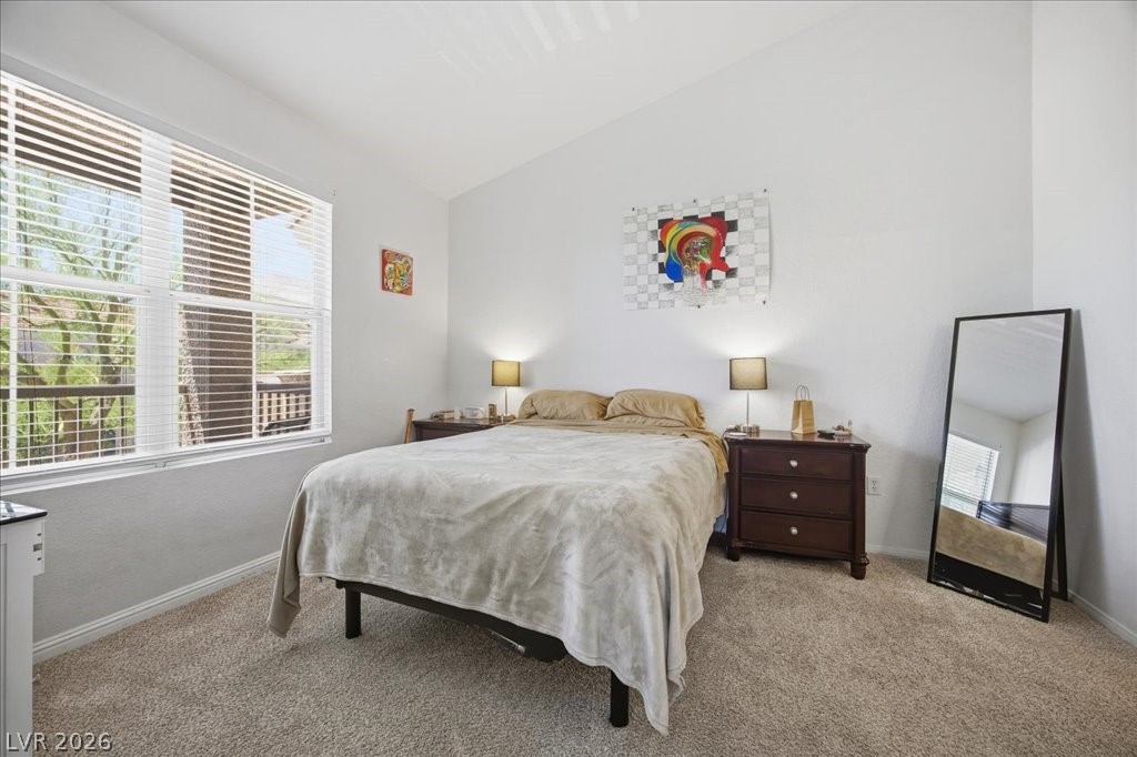 10550 West Alexander Road, Unit 2164 Las Vegas, NV 89129 - Photo 13 of 27 A comfortable bedroom features carpeted floors and a window offering a lush green outdoor view.