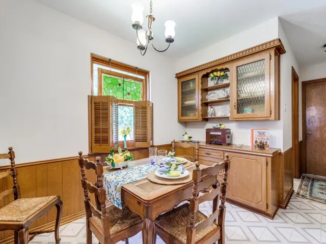 a dining room with wooden floor a chandelier a wooden table and chairs