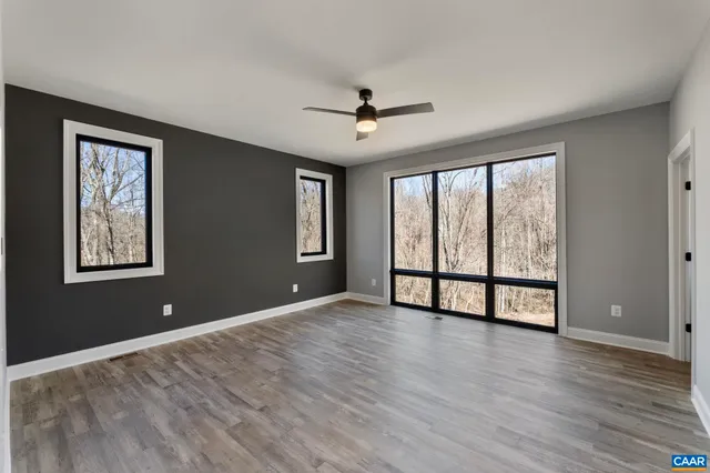 a view of an empty room with window and wooden floor