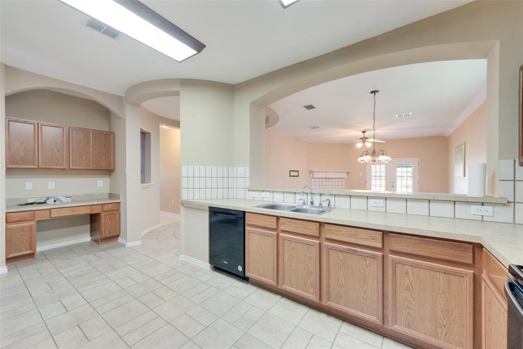 4512 Shade Tree Court Sachse, TX 75048 - Photo 7 of 19 a large kitchen with granite countertop a sink and dishwasher a stove with wooden cabinets
