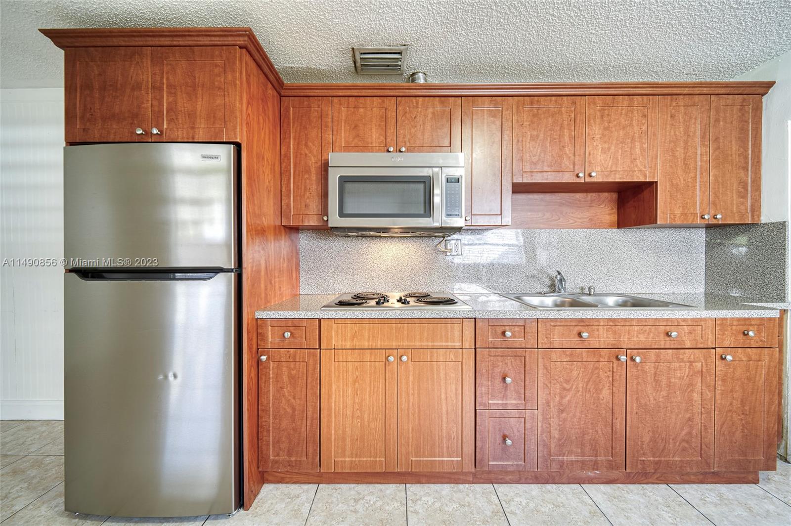 6534 Southwest 34th Street, Unit 2 Miami, FL 33155 - Photo 10 of 20 a kitchen with granite countertop wooden cabinets and a refrigerator
