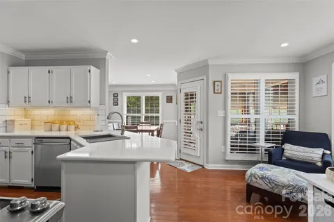 a open kitchen with granite countertop a stove a sink a refrigerator dining table and chairs with wooden floor