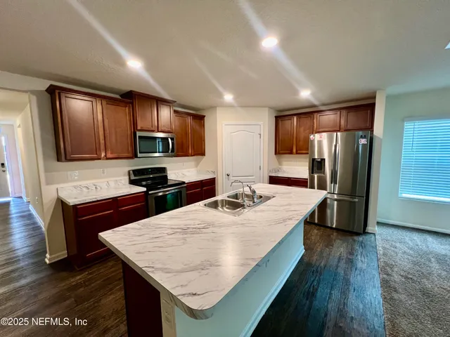 a kitchen with kitchen island granite countertop wooden cabinets a counter top space and stainless steel appliances