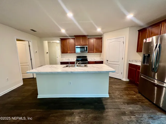 a kitchen with stainless steel appliances a refrigerator a sink a stove a microwave and wooden cabinets