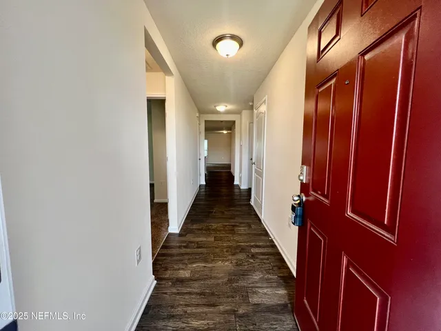 a view of a hallway with a glass door and furniture