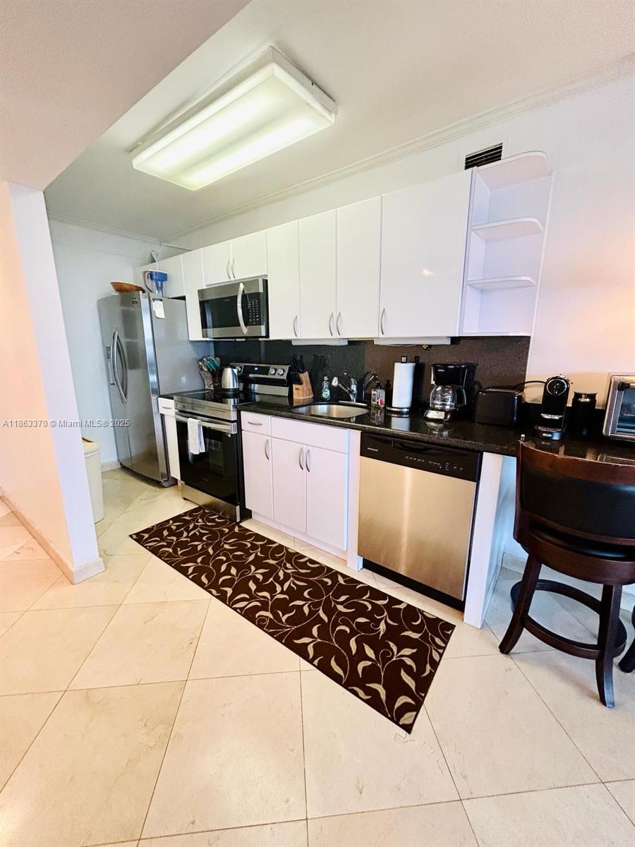 100 Lincoln Road, Unit 1034 Miami Beach, FL 33139 - Photo 5 of 11 a kitchen with stainless steel appliances kitchen island granite countertop a sink stove and refrigerator
