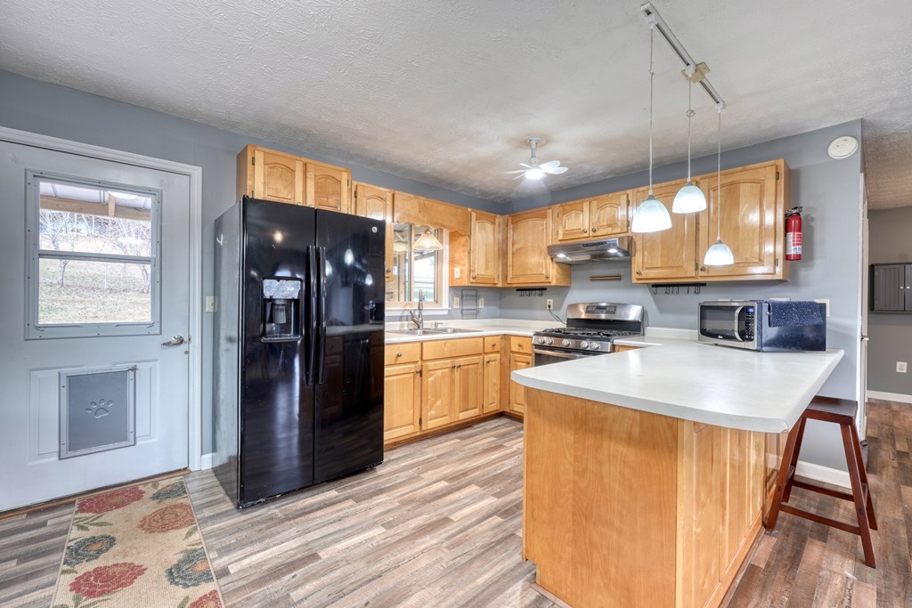 2276 Lovingood Road Hiawassee, GA 30546 - Photo 12 of 54 a kitchen with stainless steel appliances granite countertop a refrigerator a sink dishwasher a stove and white countertops with wooden floor