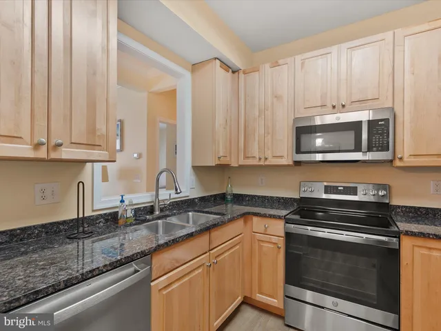 a kitchen with stainless steel appliances granite countertop a sink a stove a microwave and cabinets