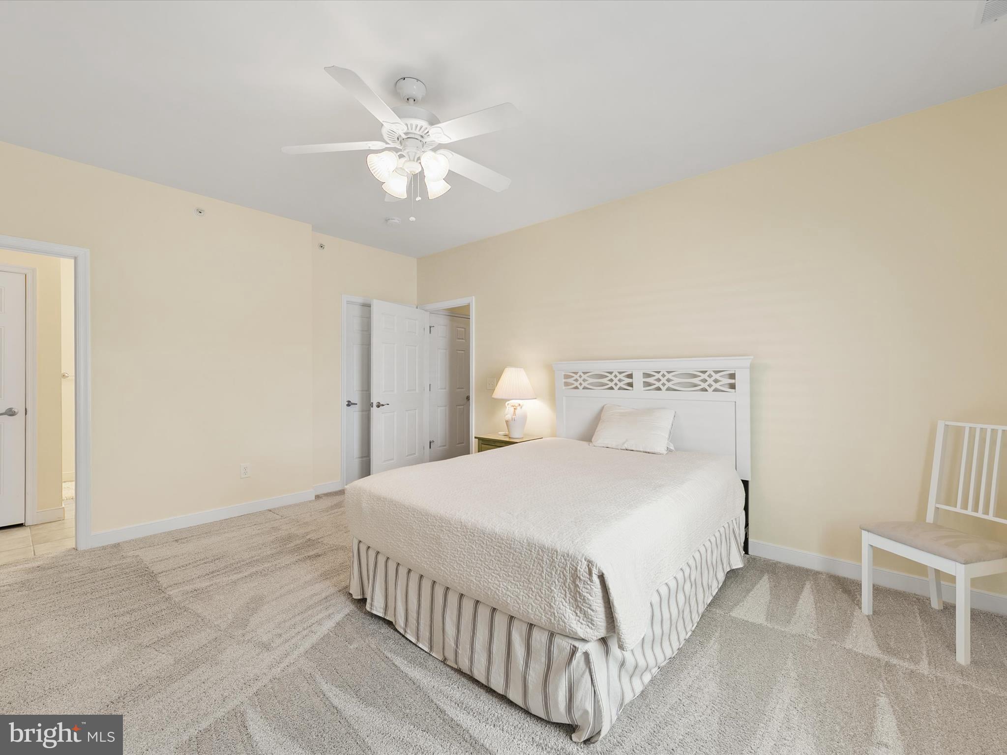 30611 Cedar Neck Road, Unit 2204 Ocean View, DE 19970 - Photo 17 of 33 a bedroom with a large bed and a chandelier