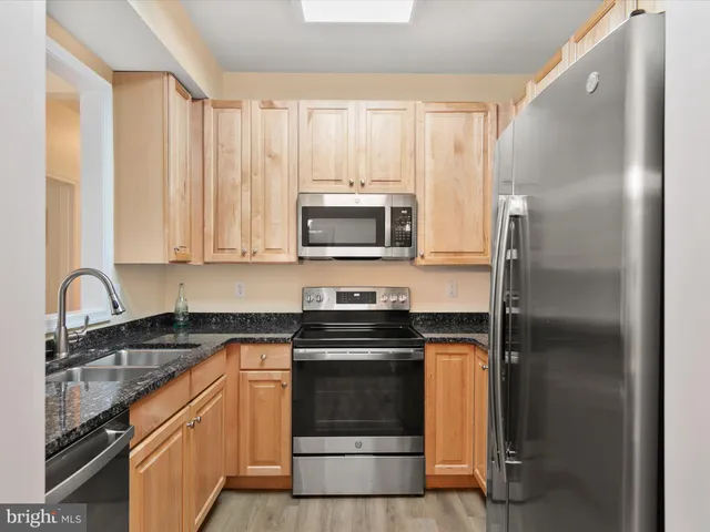 a kitchen with stainless steel appliances granite countertop a stove a refrigerator and a sink