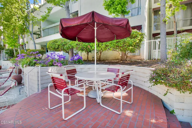 a patio with a table and chairs under an umbrella
