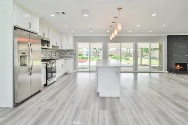 a open kitchen with stainless steel appliances granite countertop a refrigerator oven a sink dishwasher and a refrigerator with wooden floor