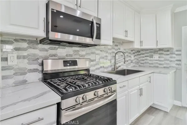a kitchen with stainless steel appliances granite countertop white cabinets a stove a sink and dishwasher