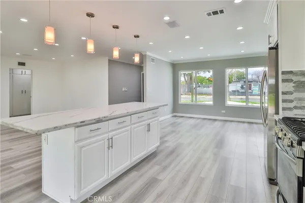 a large white kitchen with large window and stainless steel appliances