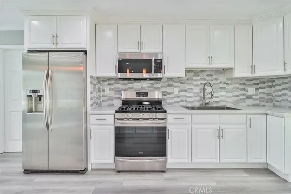 a kitchen with stainless steel appliances granite countertop a refrigerator stove and white cabinets