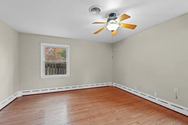 a view of an empty room with window and wooden floor