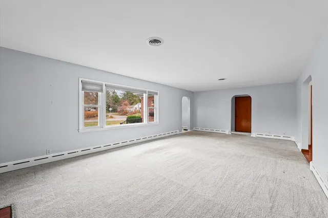 an empty room with a fireplace and window