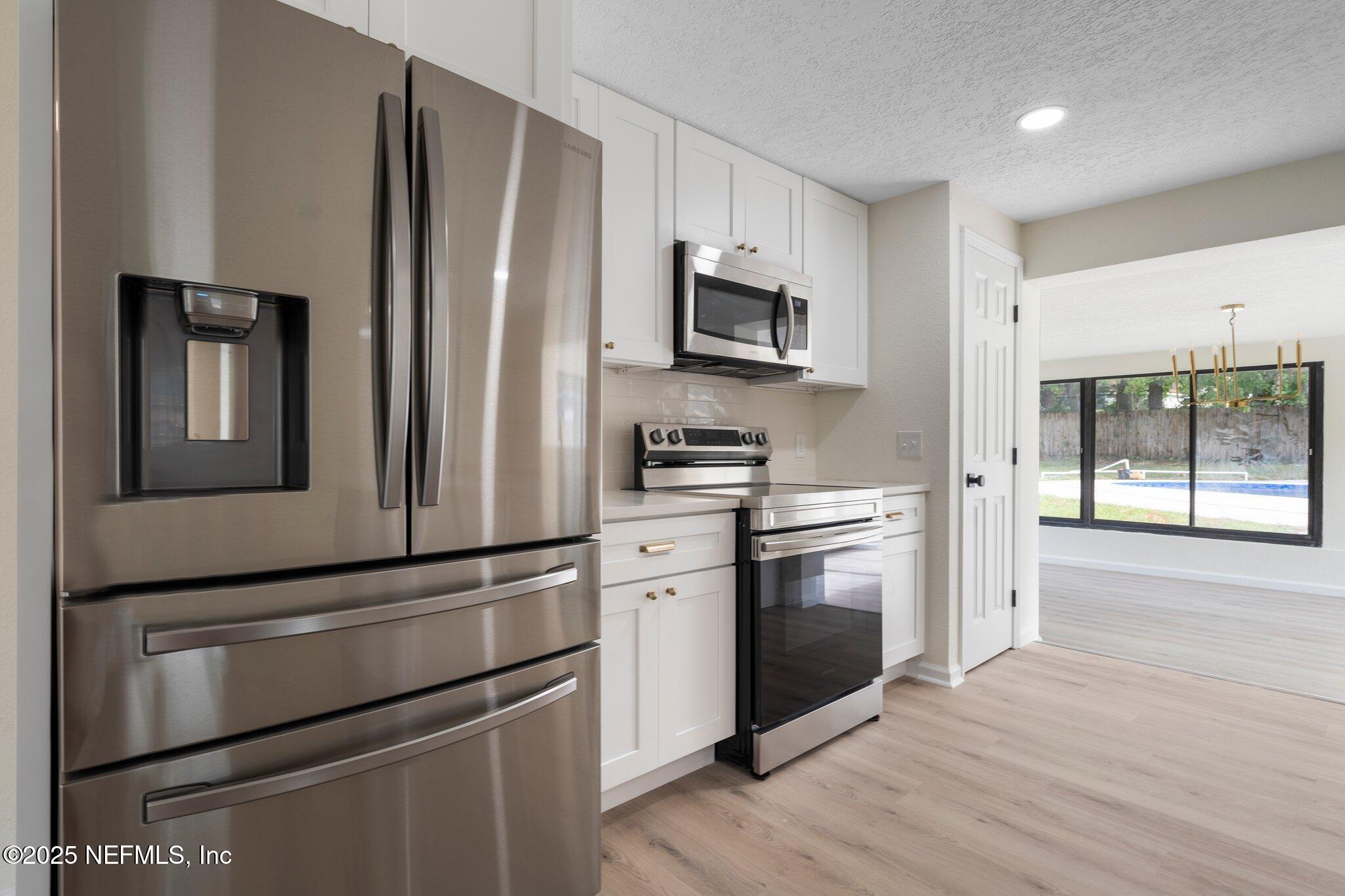 560 Aquarius Concourse Orange Park, FL 32073 - Photo 12 of 32 a kitchen with stainless steel appliances white cabinets and wooden floor