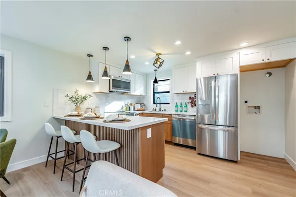 a kitchen with stainless steel appliances a dining table chairs refrigerator and sink