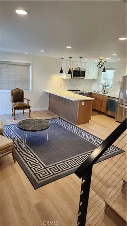 a living room with stainless steel appliances furniture and kitchen view