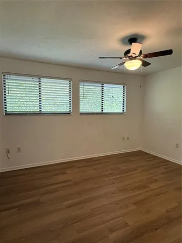 a view of empty room with wooden floor and fan