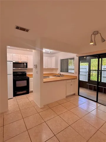 a kitchen with granite countertop white cabinets sink and window