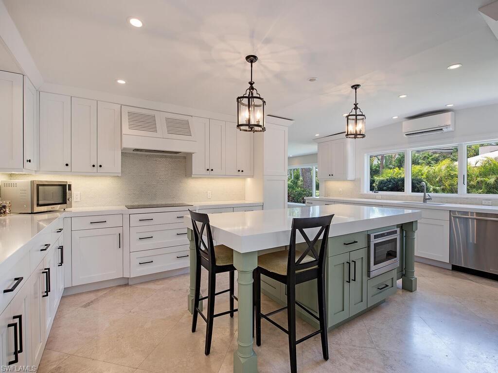 745 Pectin Road Naples, FL 34102 - Photo 7 of 18 a kitchen with stainless steel appliances a stove a sink a stove a refrigerator and white cabinets with wooden floor