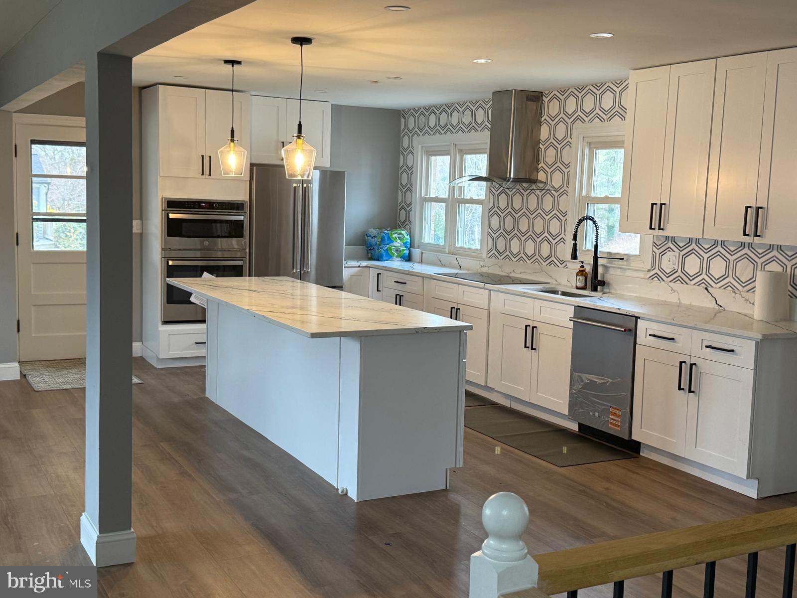 7542 Cherry Tree Drive Fulton, MD 20759 - Photo 7 of 22 a large kitchen with kitchen island a stove a sink a refrigerator and white cabinets with wooden floor