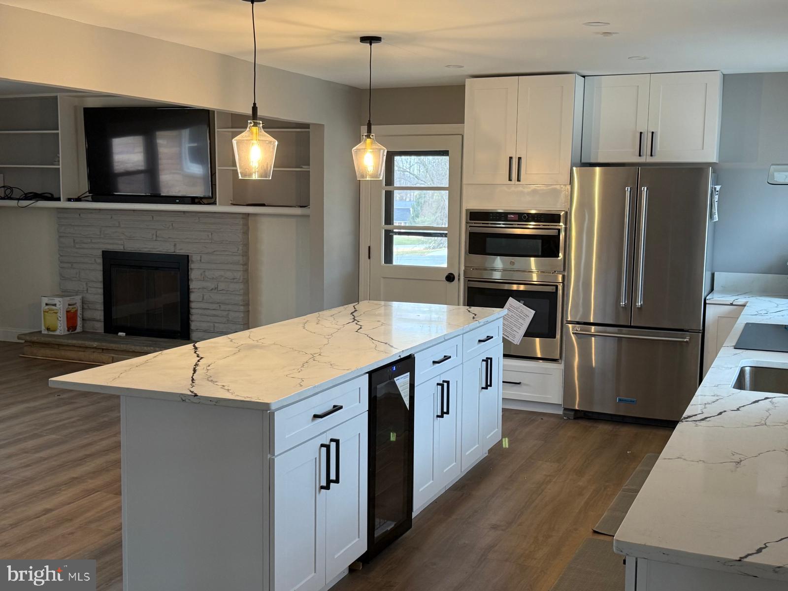 7542 Cherry Tree Drive Fulton, MD 20759 - Photo 8 of 22 a kitchen with stainless steel appliances kitchen island granite countertop a refrigerator a stove a sink dishwasher and a fireplace with wooden floor