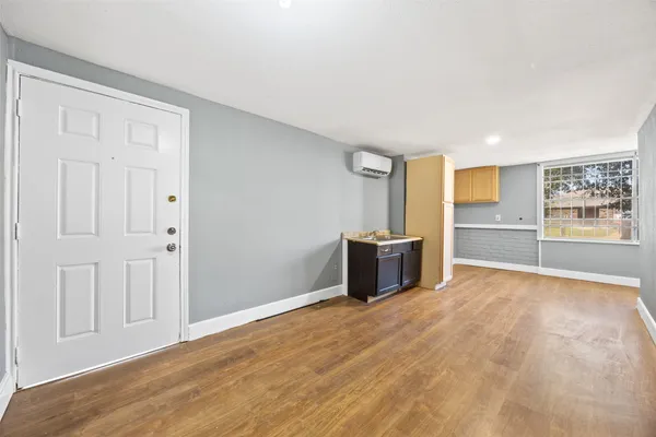 a view of an empty room with a window and wooden floor