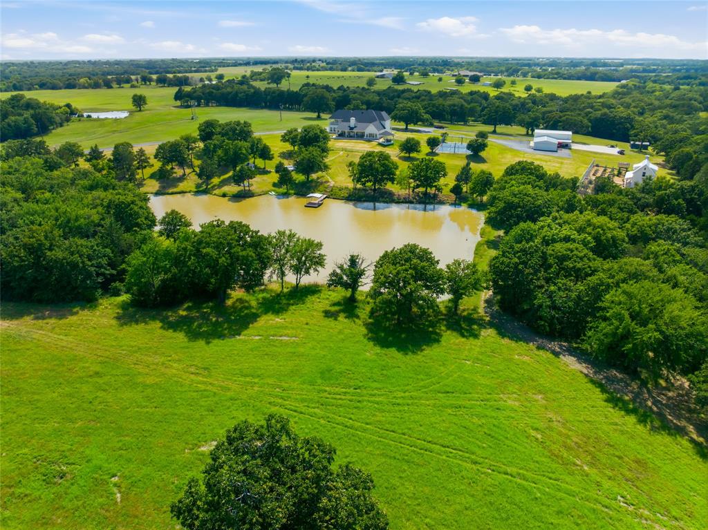 1073 Gordonville Road Gordonville, TX 76245 - Photo 27 of 38 The back aerial view of the pond and property tells the story here - a beautiful house, ponds, rolling hills, am gorgeous trees, a green house and garden, a pickleball court and a double garage with 2 RV spaces and 2 garage spaces with plenty of shop space in between.