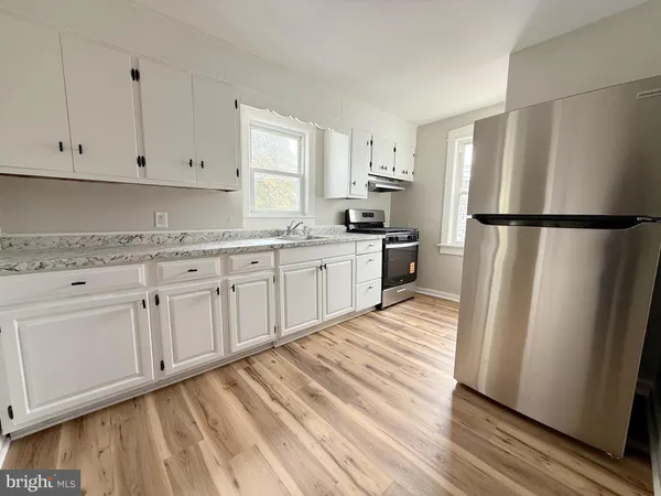 a kitchen with white cabinets and refrigerator