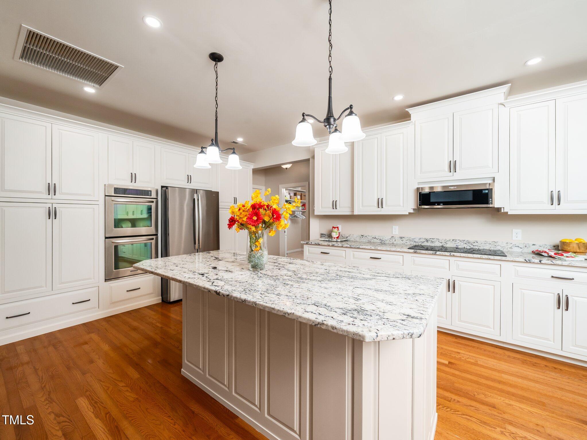 8917 Thompson Mill Road Wake Forest, NC 27587 - Photo 11 of 42 a kitchen with kitchen island granite countertop a sink cabinets and wooden floor