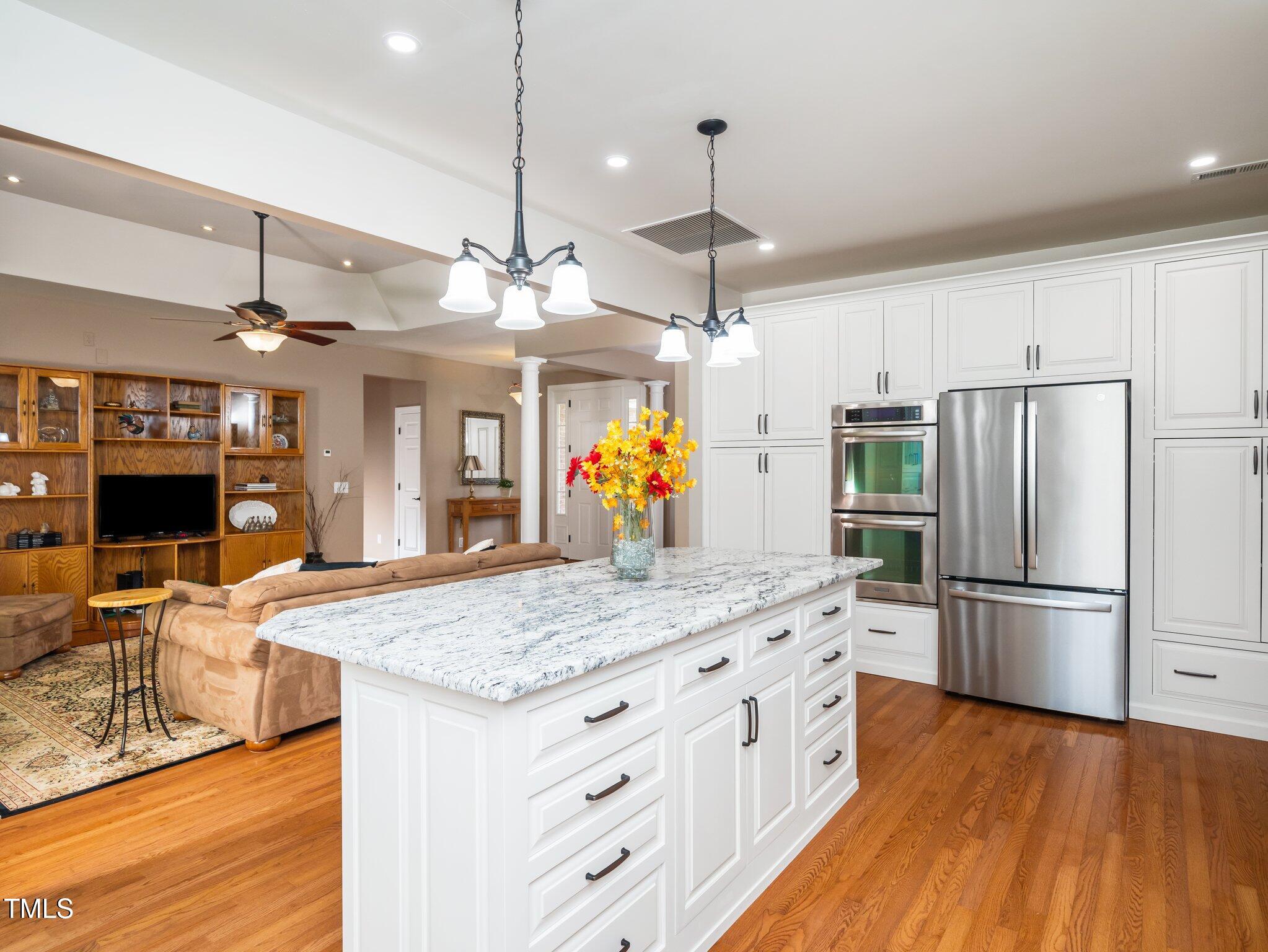 8917 Thompson Mill Road Wake Forest, NC 27587 - Photo 14 of 42 a kitchen with stainless steel appliances kitchen island granite countertop a refrigerator a sink dishwasher a dining table and chairs with wooden floor