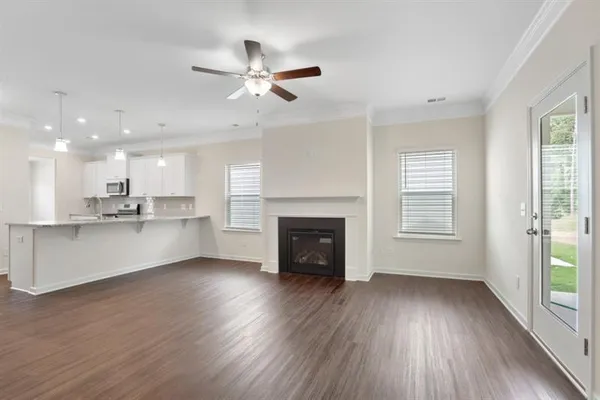a view of an empty room with wooden floor and a kitchen